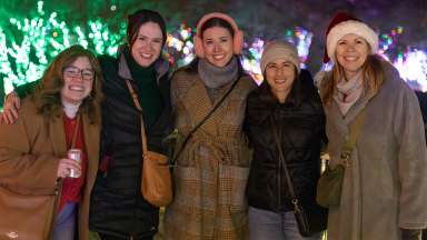 five smiling adults outdoors in winter attire enjoying Merry and Bright