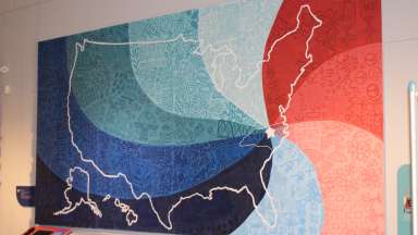 a colorful quilt hanging on a wall as an exhibit