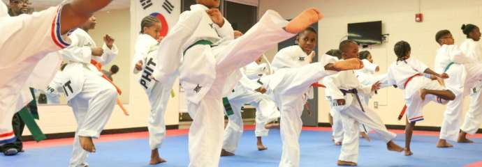 kids kicking high in the air in a martial arts class