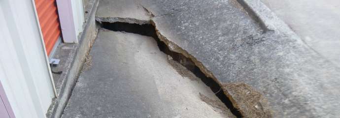 A crack in pavement from a failing stormwater pipe that's close to the entrance of a storage facility