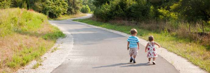 Two little kids walking along a greenway trail