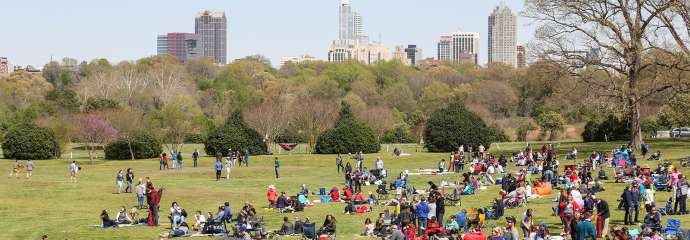 Event at Dix Park with Raleigh skyline in the background and lots of people out on a green lawn