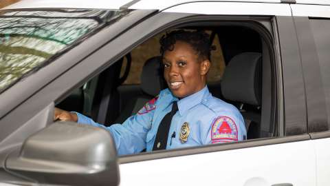 Female Raleigh Police Officer in a patrol car smiling at camera