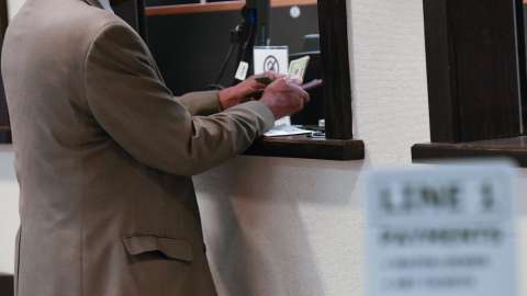 hands of a customer paying with cash at a teller window