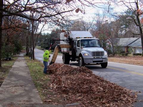 Collection truck vacuuming leaves from side of road