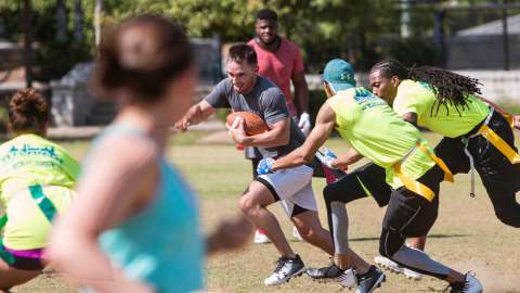 Group of people playing flag football. Person grabbing the flag from the other team member.