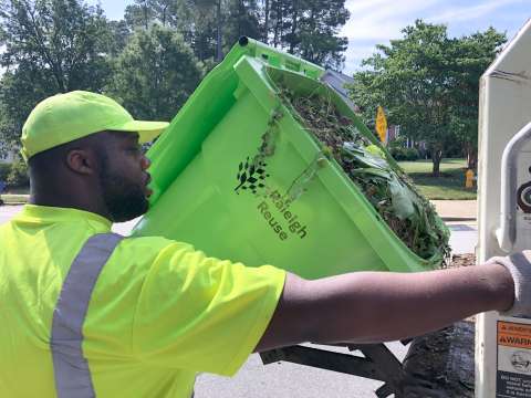 SWS crew member collecting curbside yard waste cart.