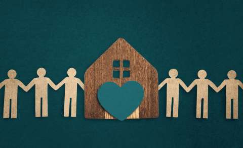 cut out paper of people holding hands with a house and heart in the center