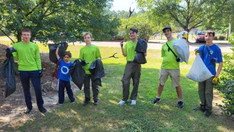 a group of smiling volunteers with litter grabbers and trash bags