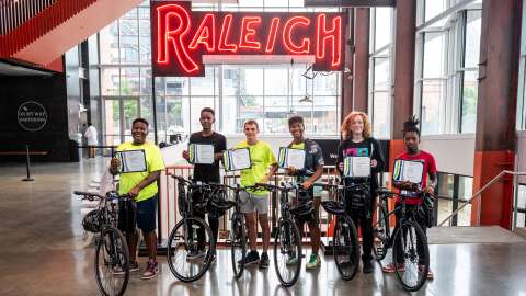 Commute Smart Academy participants holding certificates and standing with their bikes