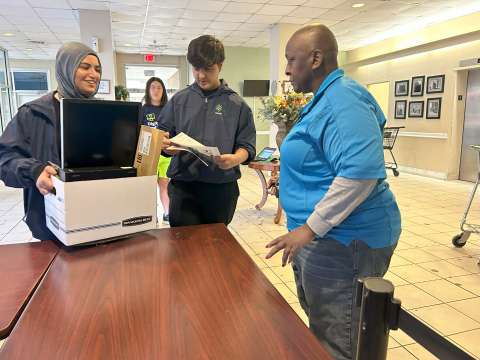 teenage girl and boy donating a desktop to a lady