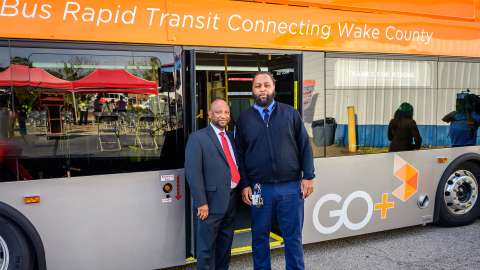 A GoTriangle bus with a driver and another person posing in front of the bus