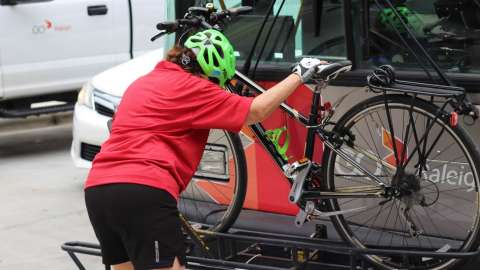 woman loading bike on to bus bike rack