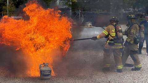 Firefighters extinguish a turkey fryer in flames during a demonstration