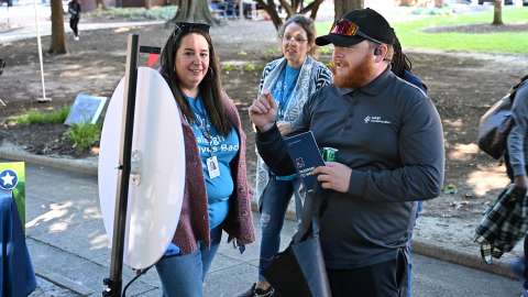 A Raleigh Transportation employee plays a game at the Wellness Fair with two people looking on.