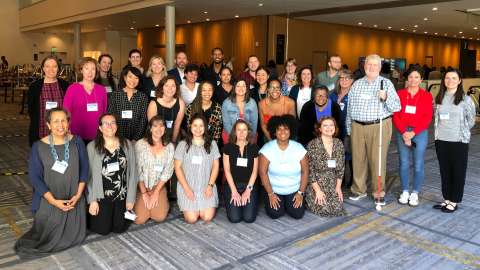 Photo of a group of smiling community members in a convention center setting