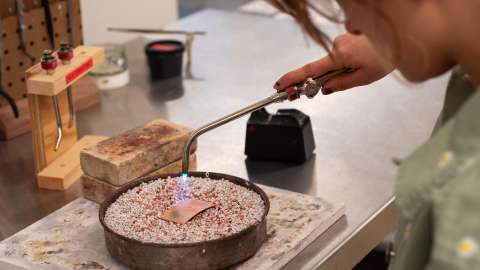Student uses torch to work on metal piece