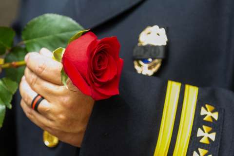Firefighter in dress uniform holding red rose flower