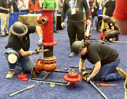 Women utility workers competing at a fire hydrant competition