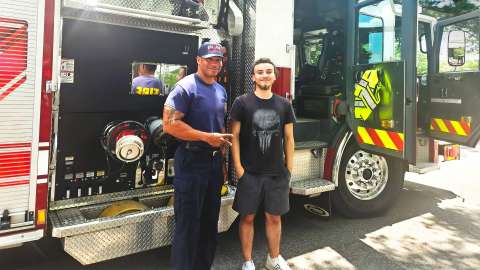 Raleigh firefighter in front of fire engine with community youth member