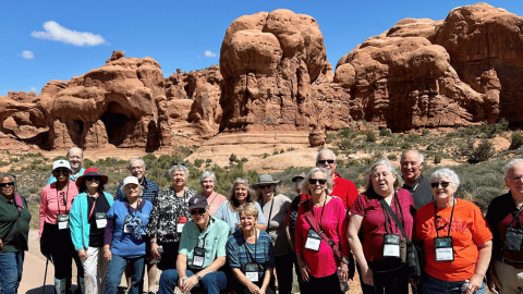 Group of active adults standing in front of a mountain top