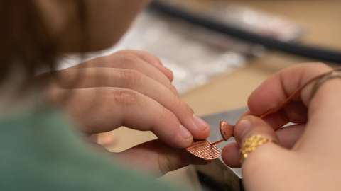 Student working on a piece of copper jewelry
