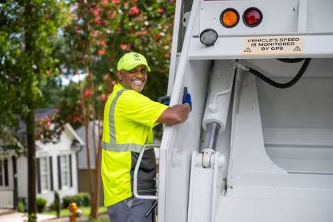 Solid Waste crew member on the back of a collection truck