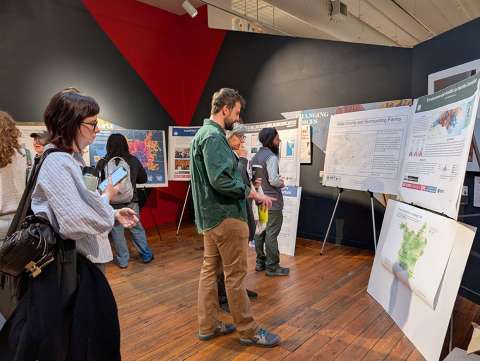 Visitors at the 2025 GIS Day event look at posters created using GIS technology.