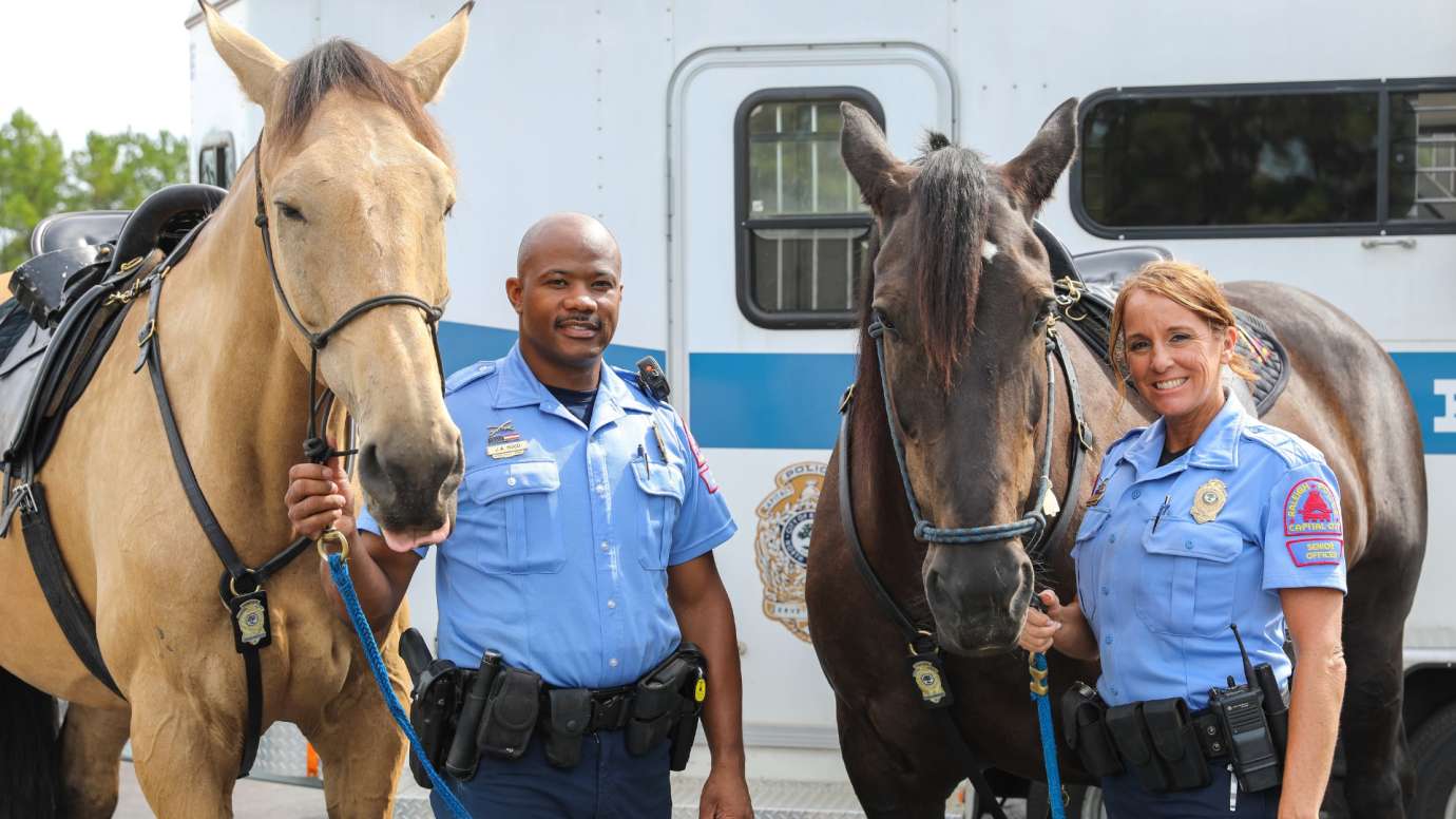 male and female raleigh police mounted officers next to their horses