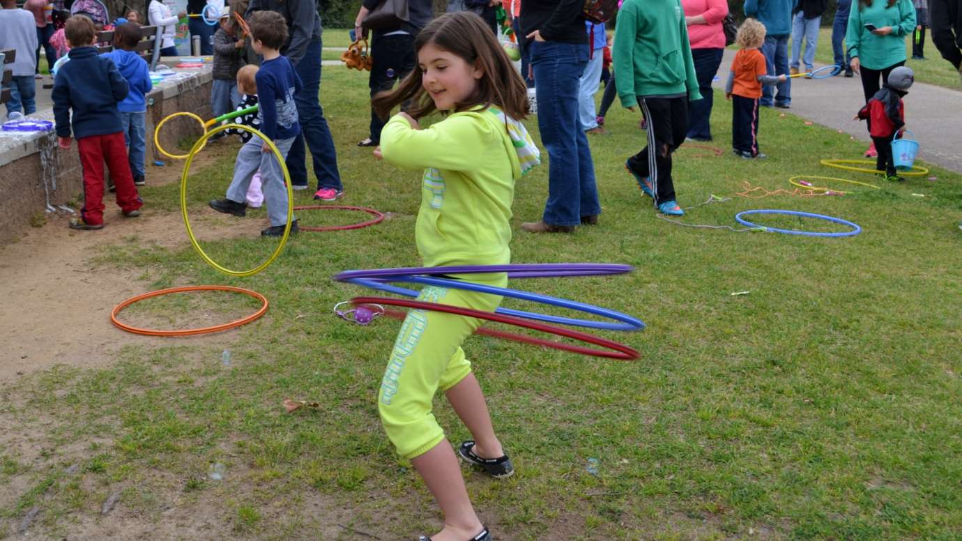 Girl tries using three hula hoop rings at the same time near a picnic shelter at Anderson Point Park