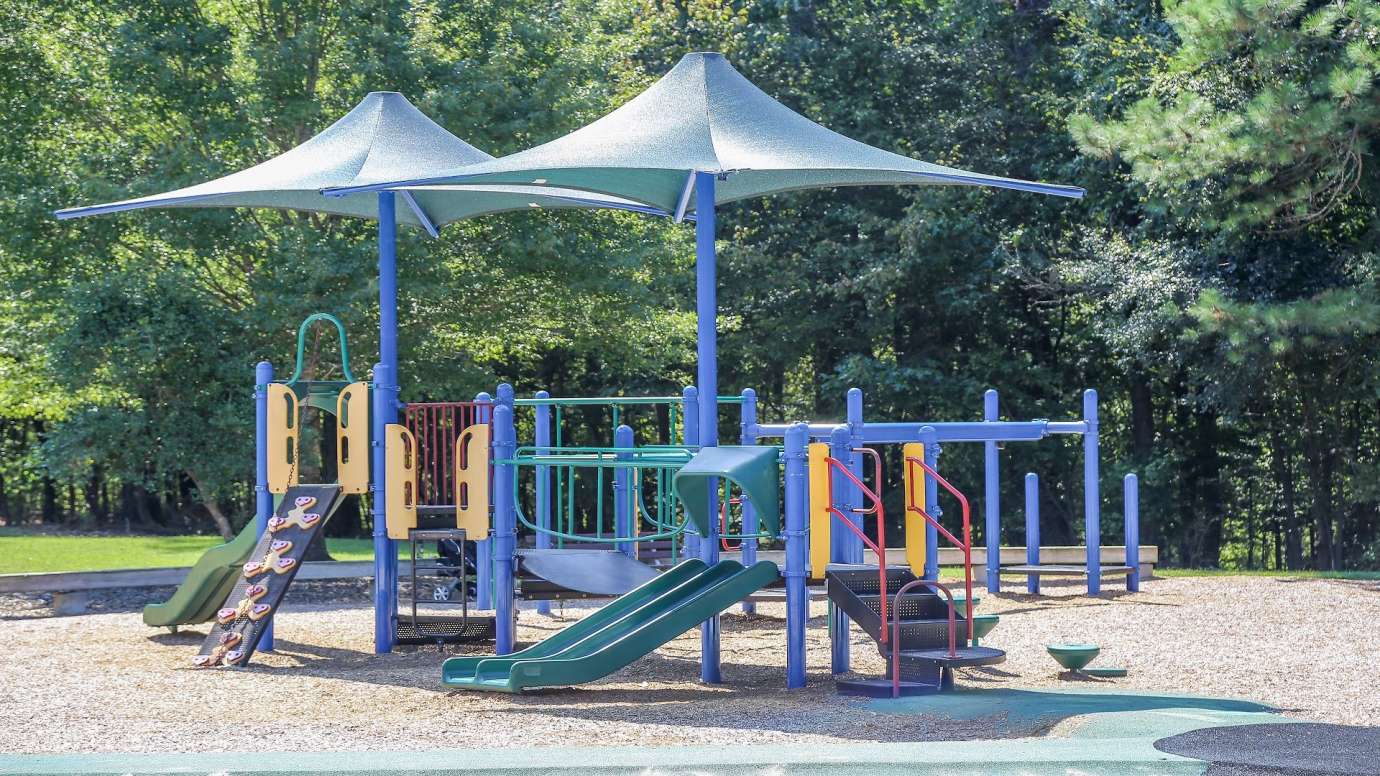 playground structure with slides and other climbing equipment under a canopy
