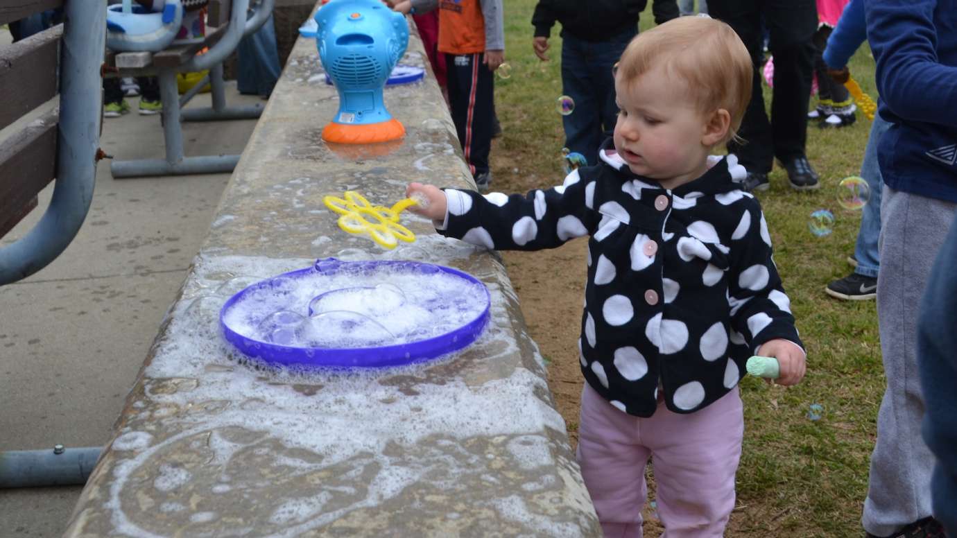 Small toddler girl uses large bubble pan to soak her wand