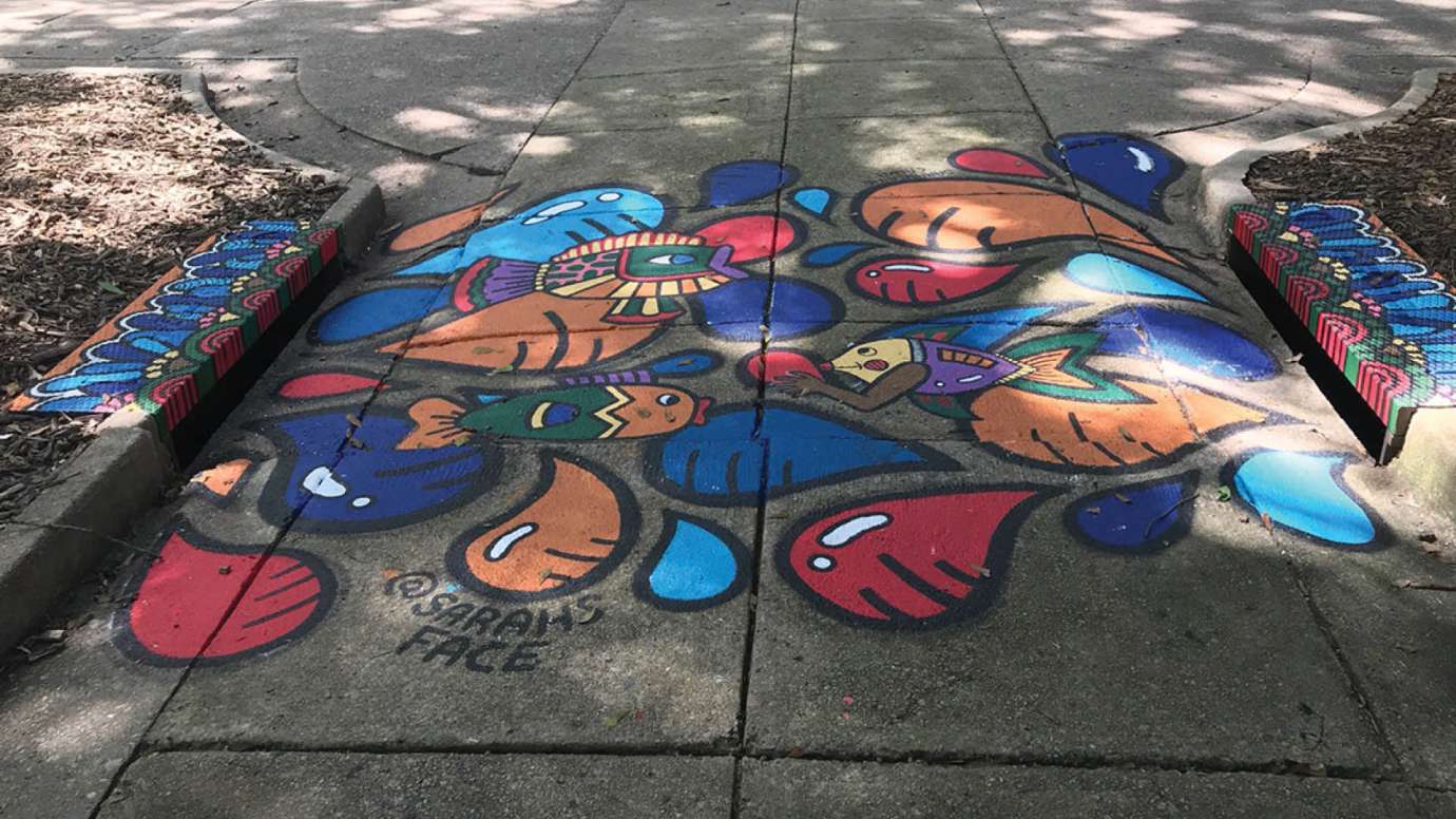A storm drain mural in Nash Square Park with colorful fish and raindrops.