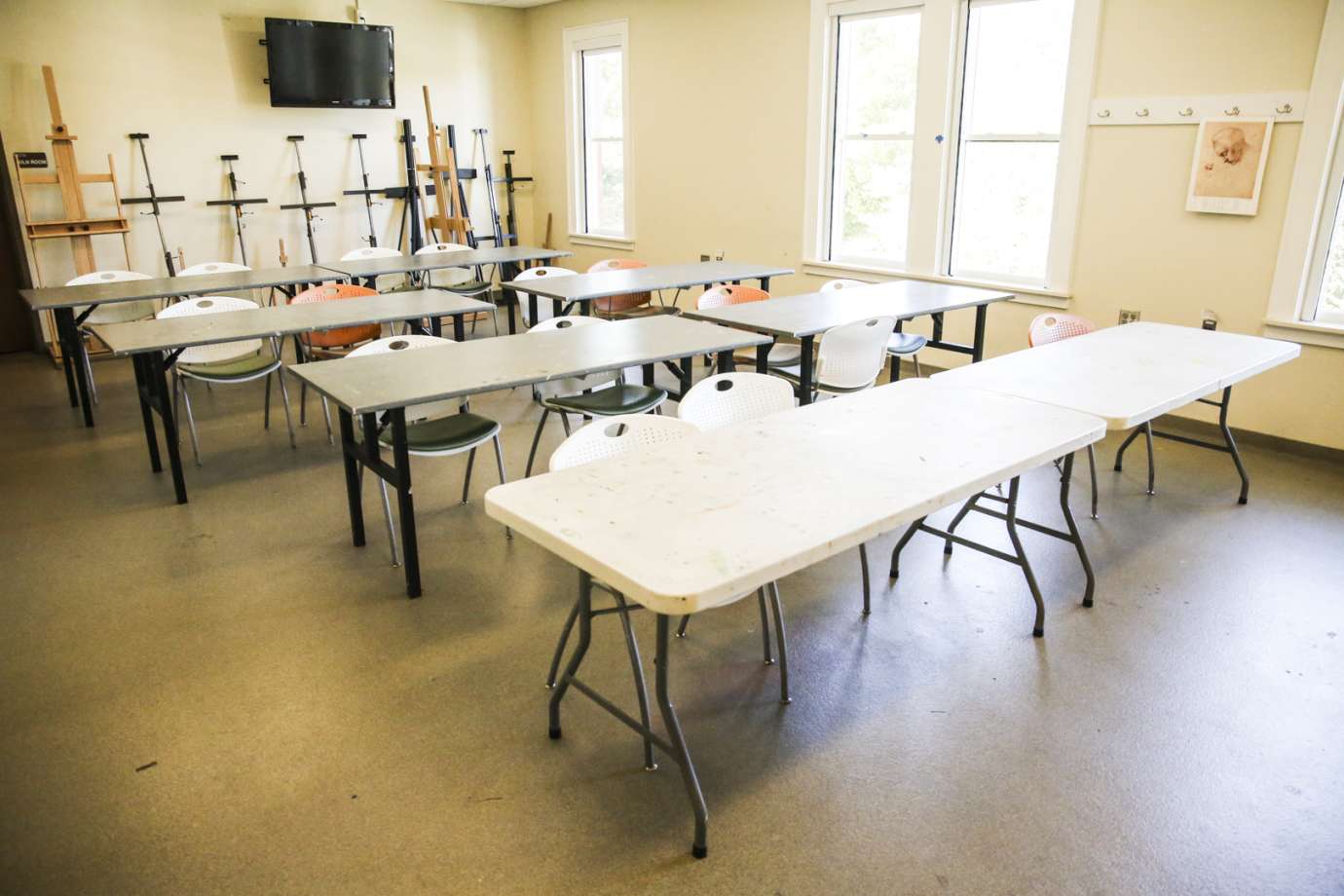 A classroom with tables, chairs and easels 