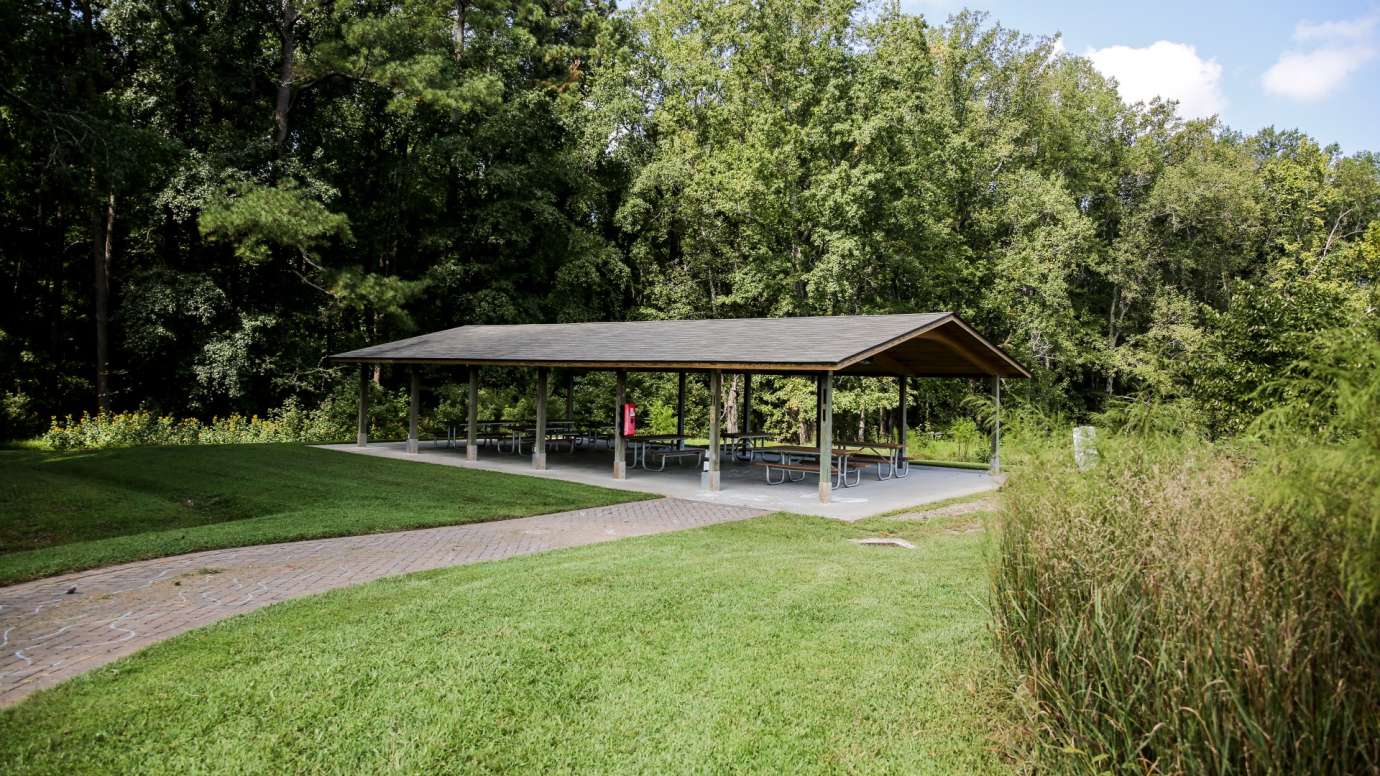 A large outdoor picnic shelter with multiple tables 