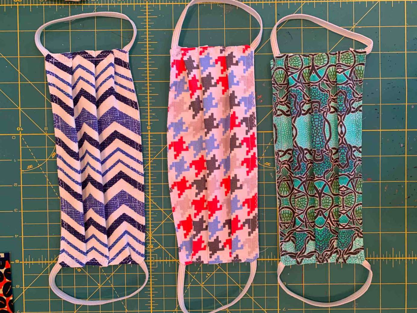Three facemasks made from brightly, patterned fabric and elastic.