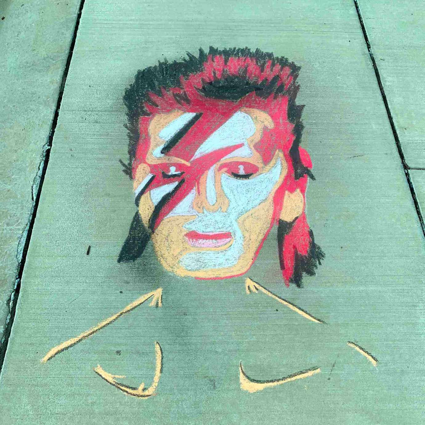 A sidewalk chalk drawing of David Bowie with red lightning strike across face