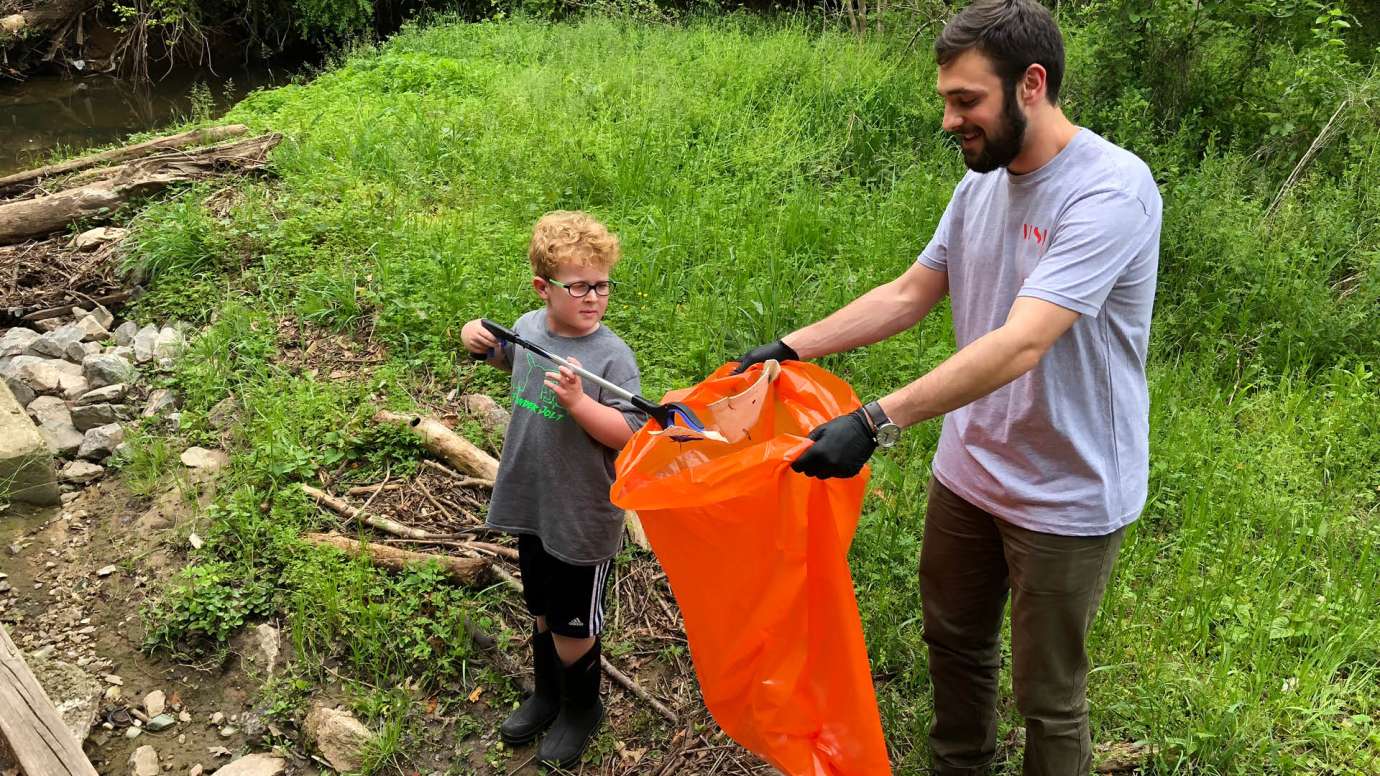 Two volunteers putting trash from the stream in a garbage bag