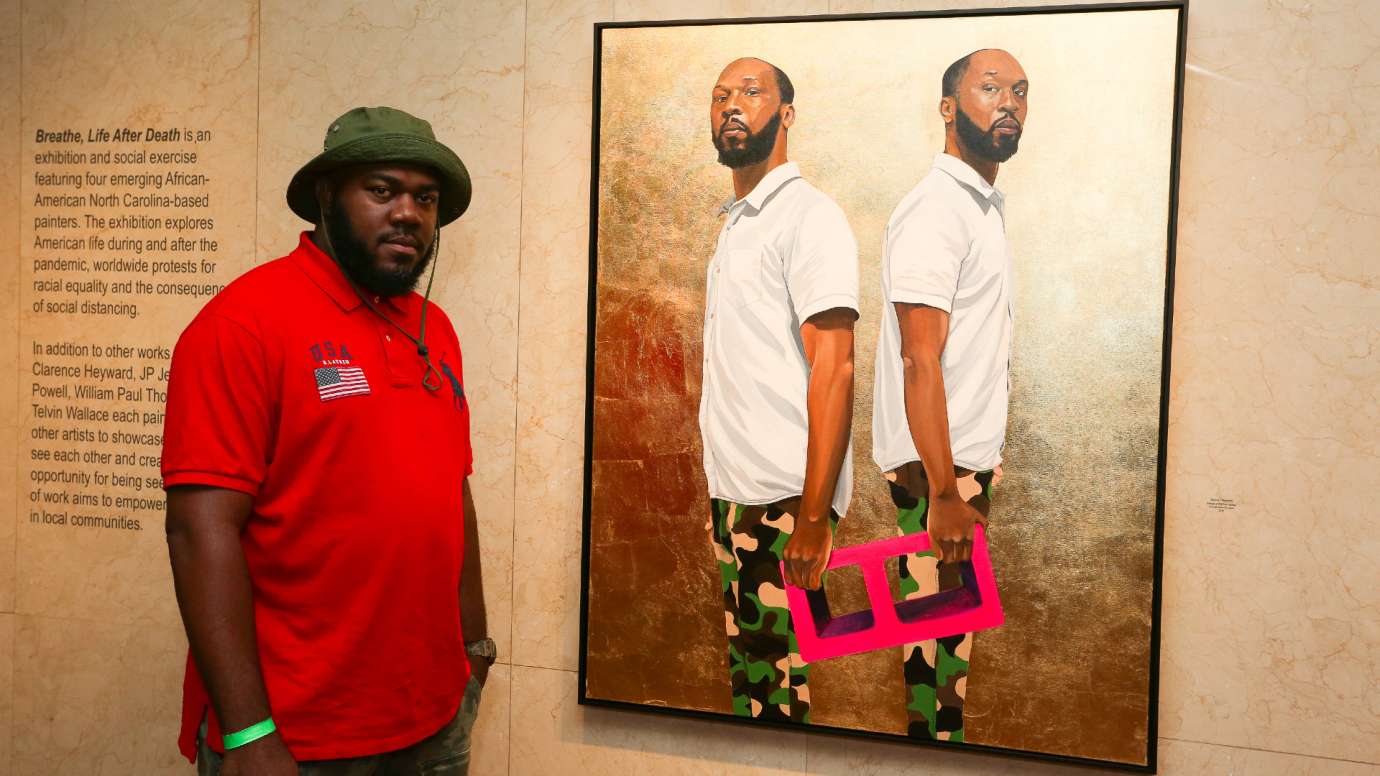 Clarence Heyward stands next to his portrait of William Paul Thomas