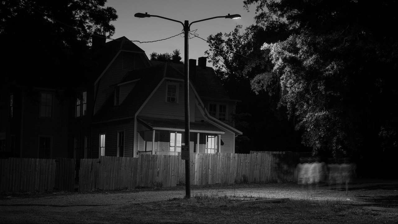 Archival pigment print by Adam Bellefeuil, a house, fence, street light, and blurry person on the road