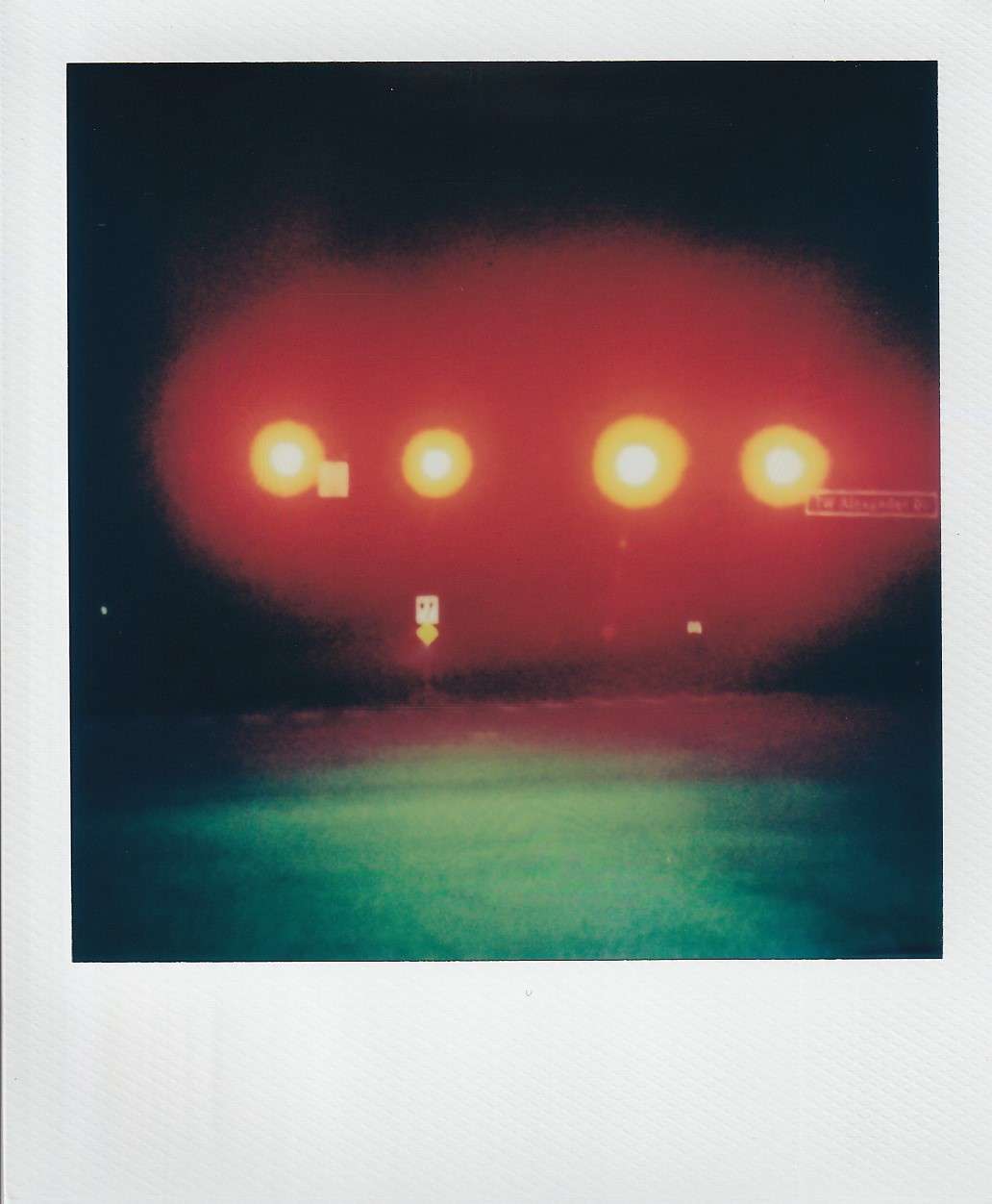 Polaroid photograph by I'Nasah Crockett, red stop lights glowing at night