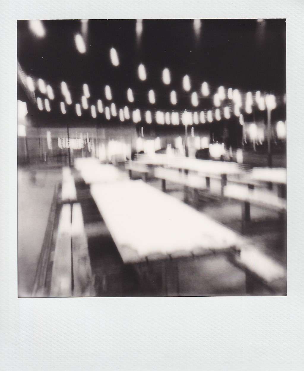 Polaroid photography by I'Nasah Crockett, string lights hanging over long tables and benches at night