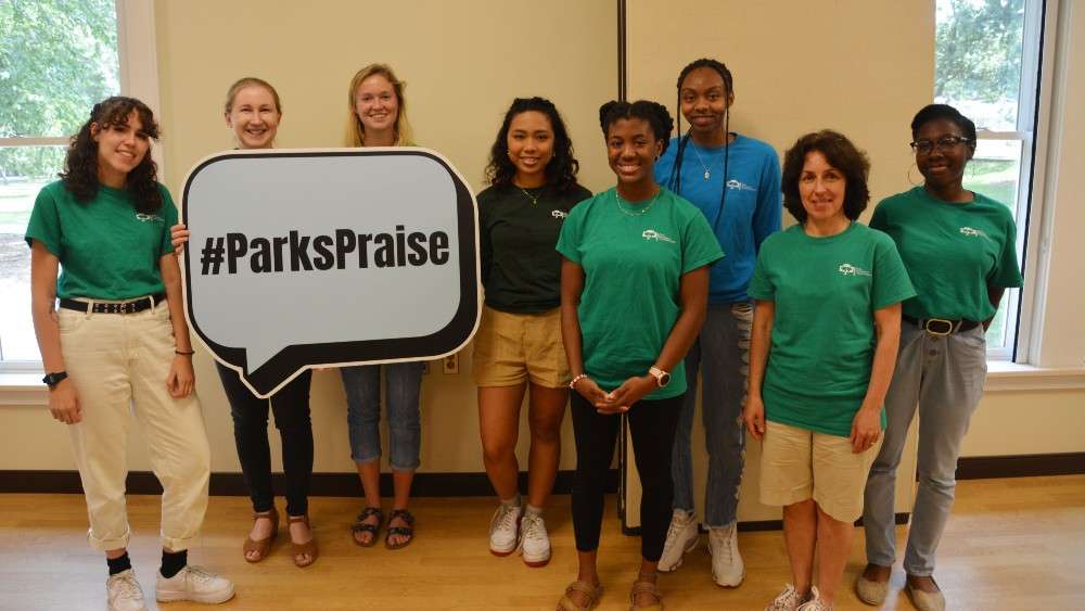 Art camp staff holding Parks Praise sign