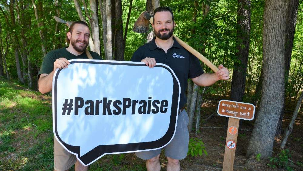 Two parks staff holding Parks praise sign