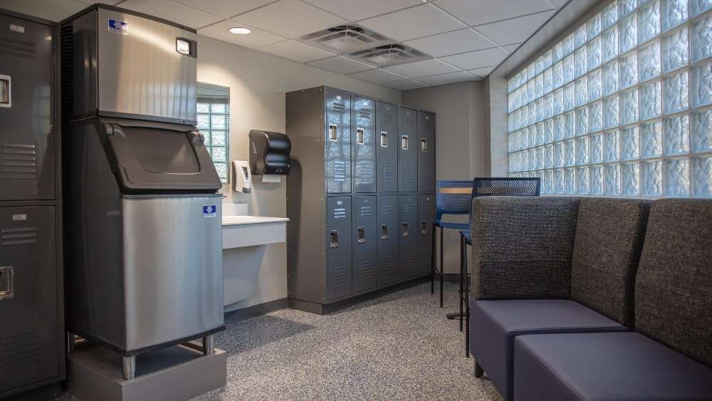 Indoor locker room space with bench, ice machine, sinks and lockers