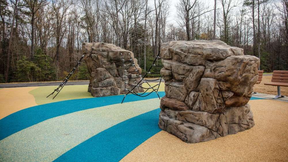 Two large climbing boulders with netting to climb up on rubberized surface playground