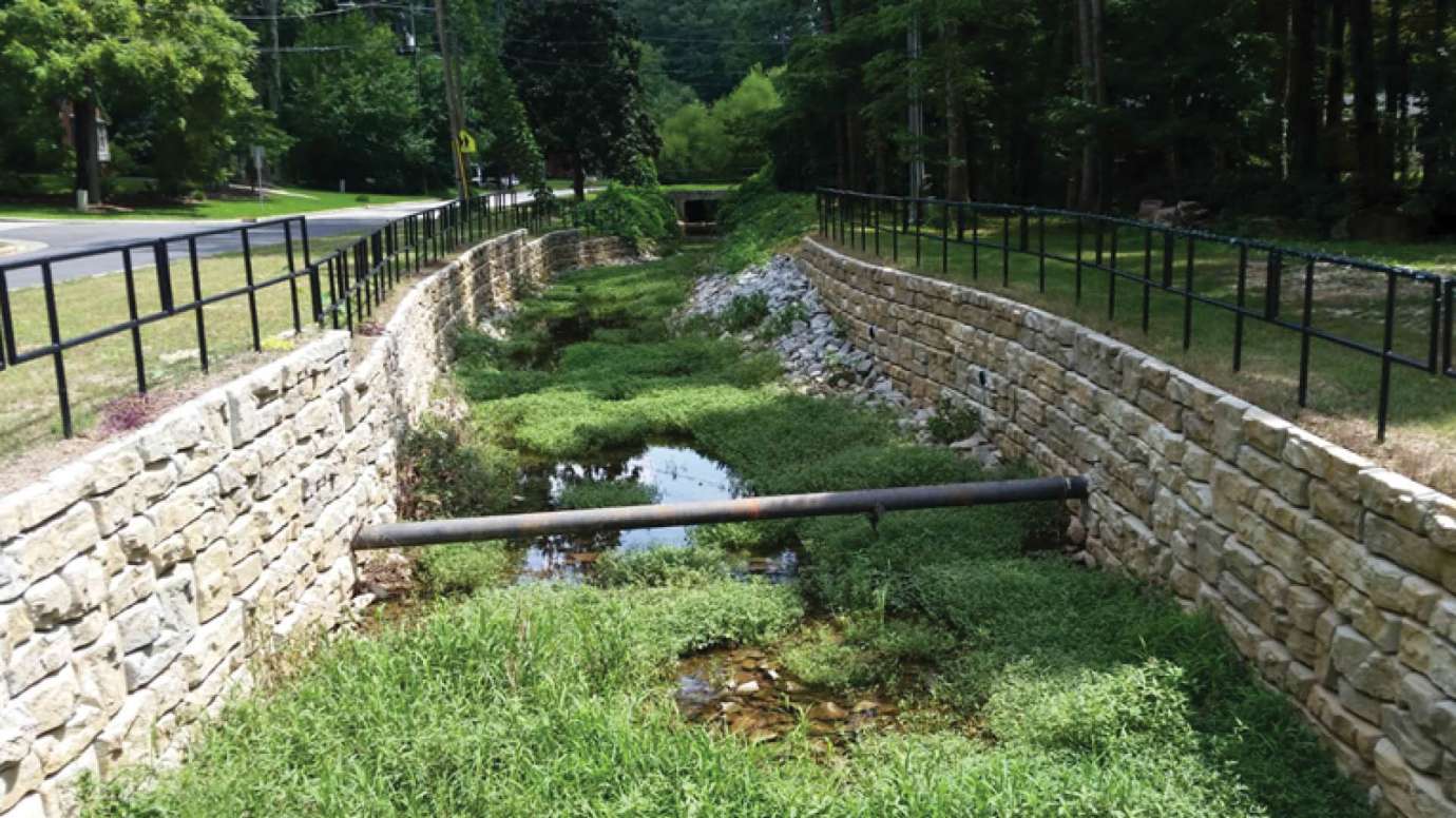A channel with two stone walls running along it to control how stormwater flows along Swift Drive
