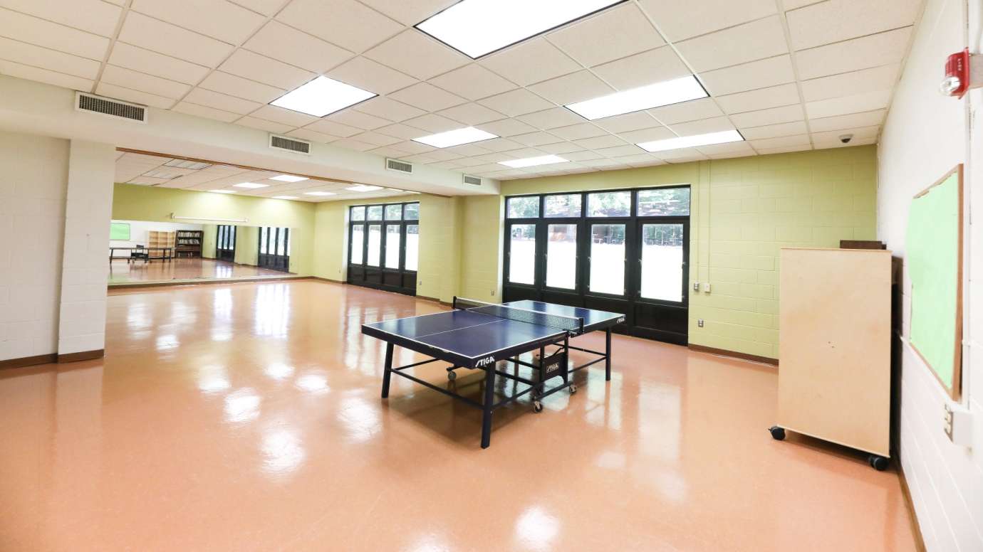 A large open game room with a ping pong table, foosball table and TV