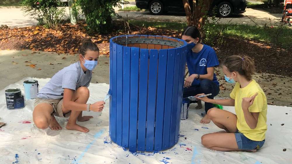 Girl scout troop painting trash can blue