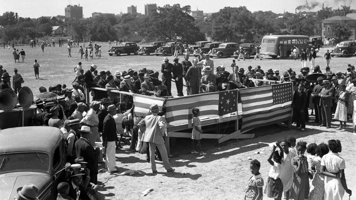 Historic image of people at Chavis park dedication on stage with American flags